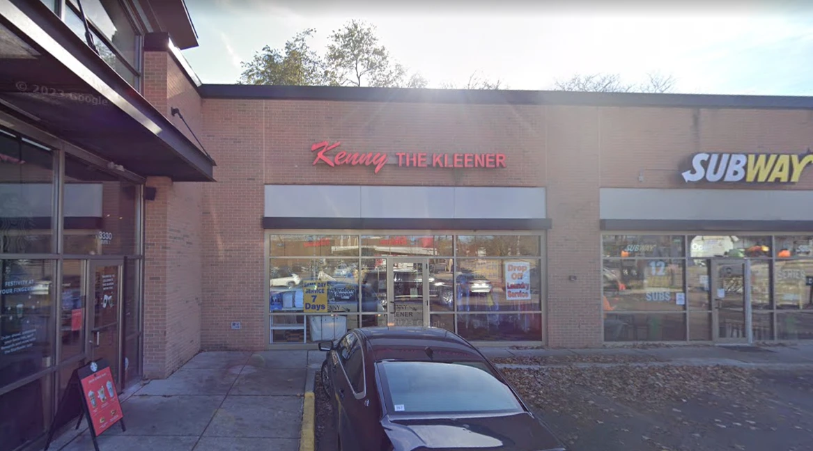 A strip mall storefront for "Kenny the Kleener" with a parked car in front; Subway restaurant is visible to the right.